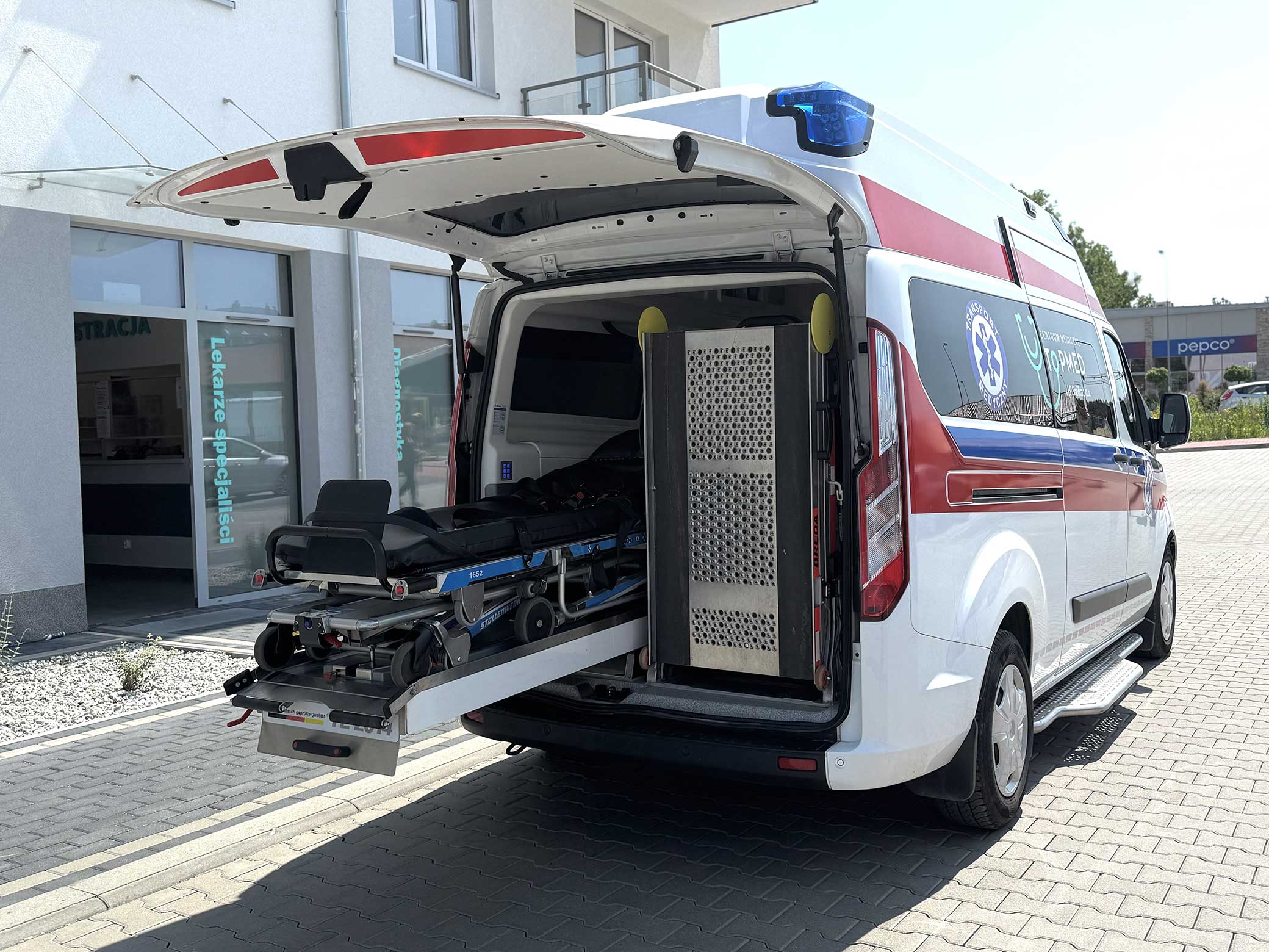 tył karetki z otwartymi drzwiami wysuniętymi noszami